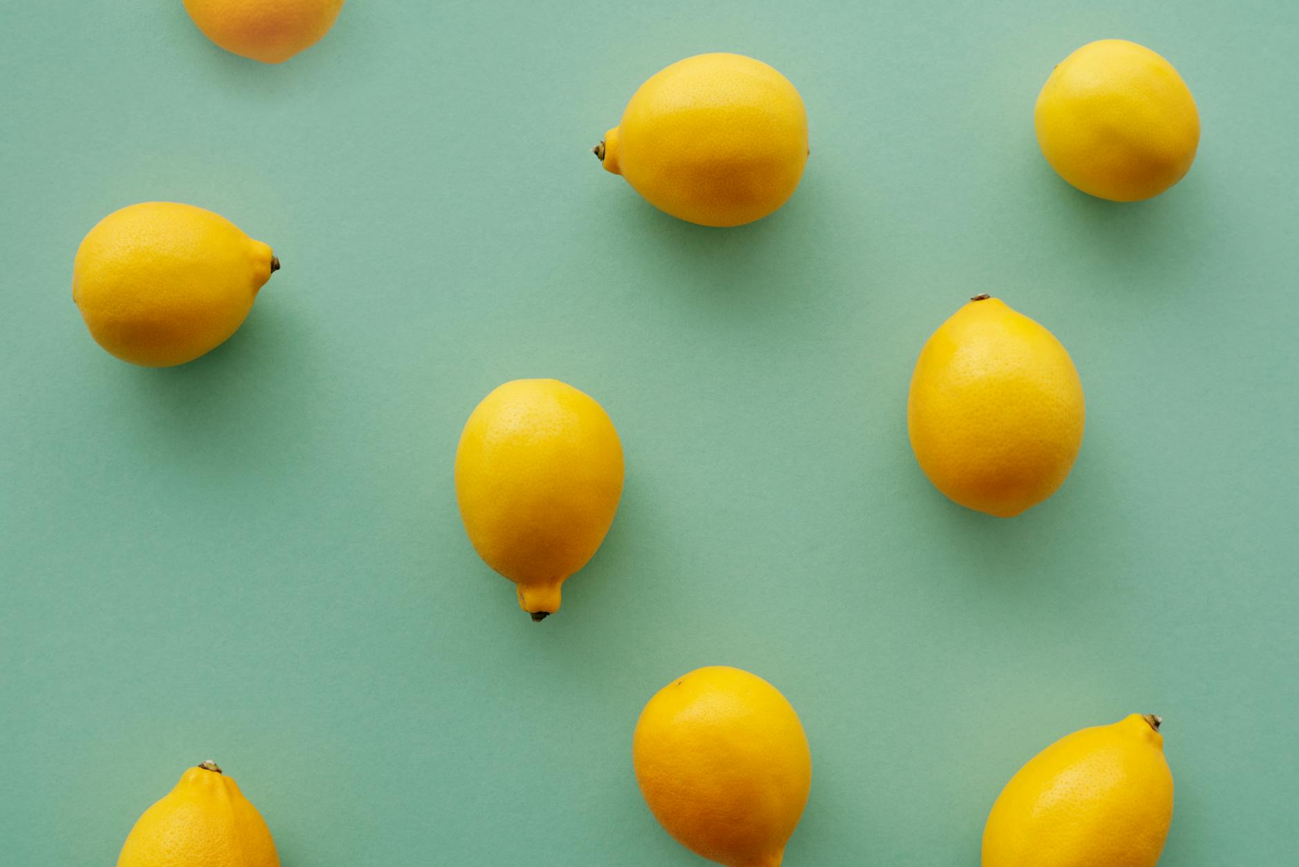 Bright yellow lemons arranged on a pastel green background, symbolizing the range of approaches to lemon vibrator pleasure.