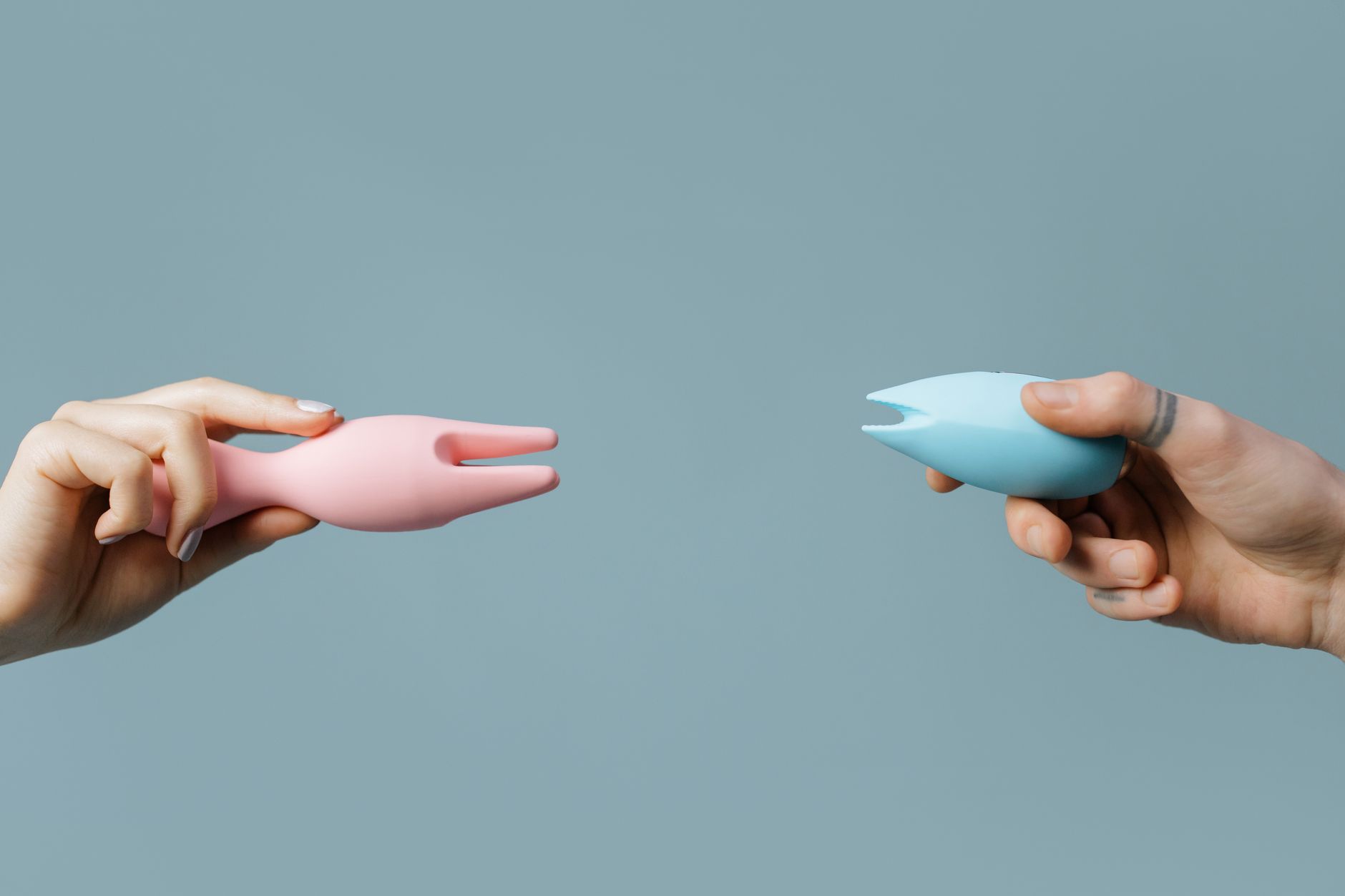 Mani che tengono vibratori in silicone rosa e blu