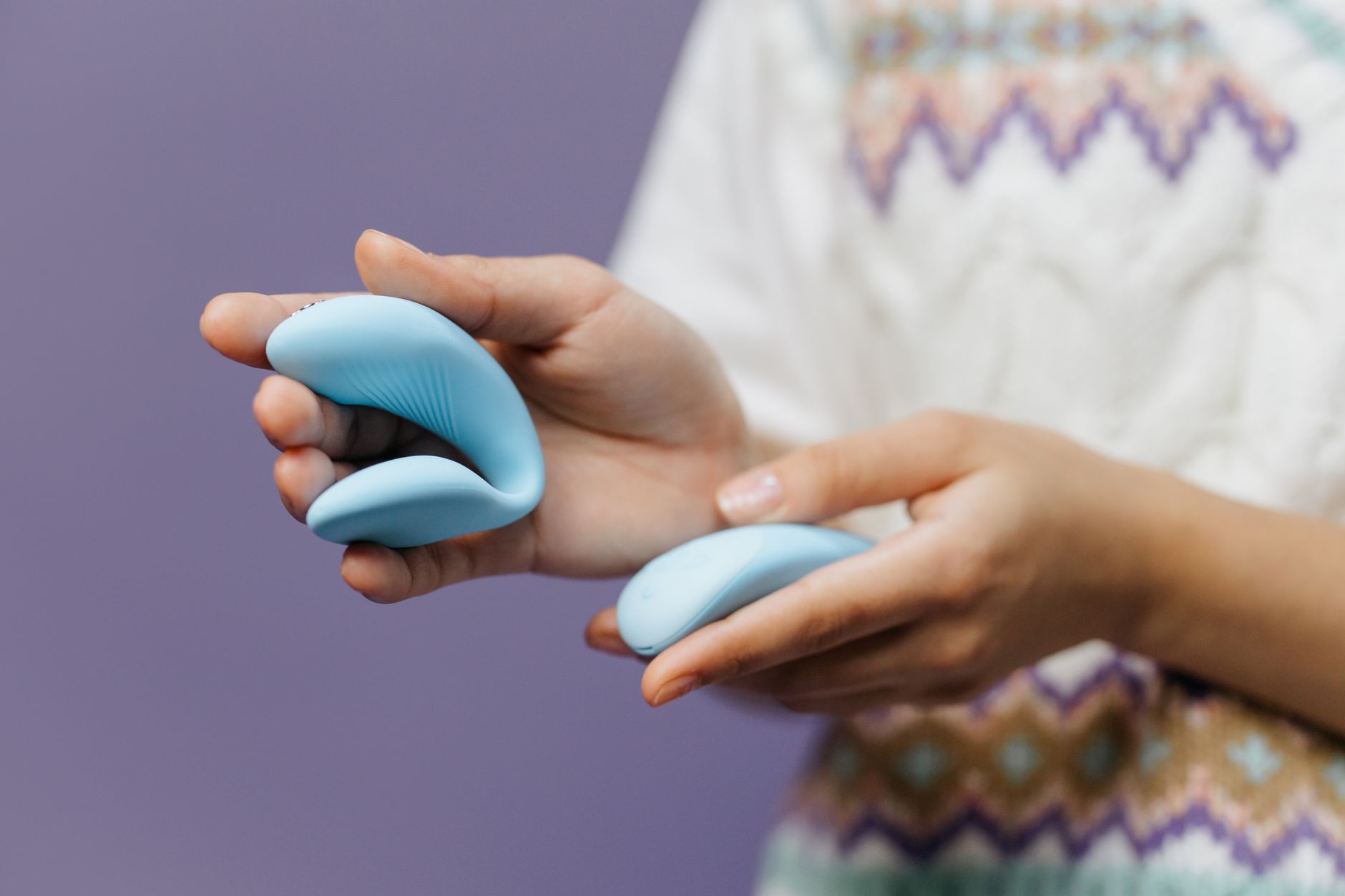 Intimate hands holding a sleek lemon vibrator against a soft background, representing couple's shared intimacy.