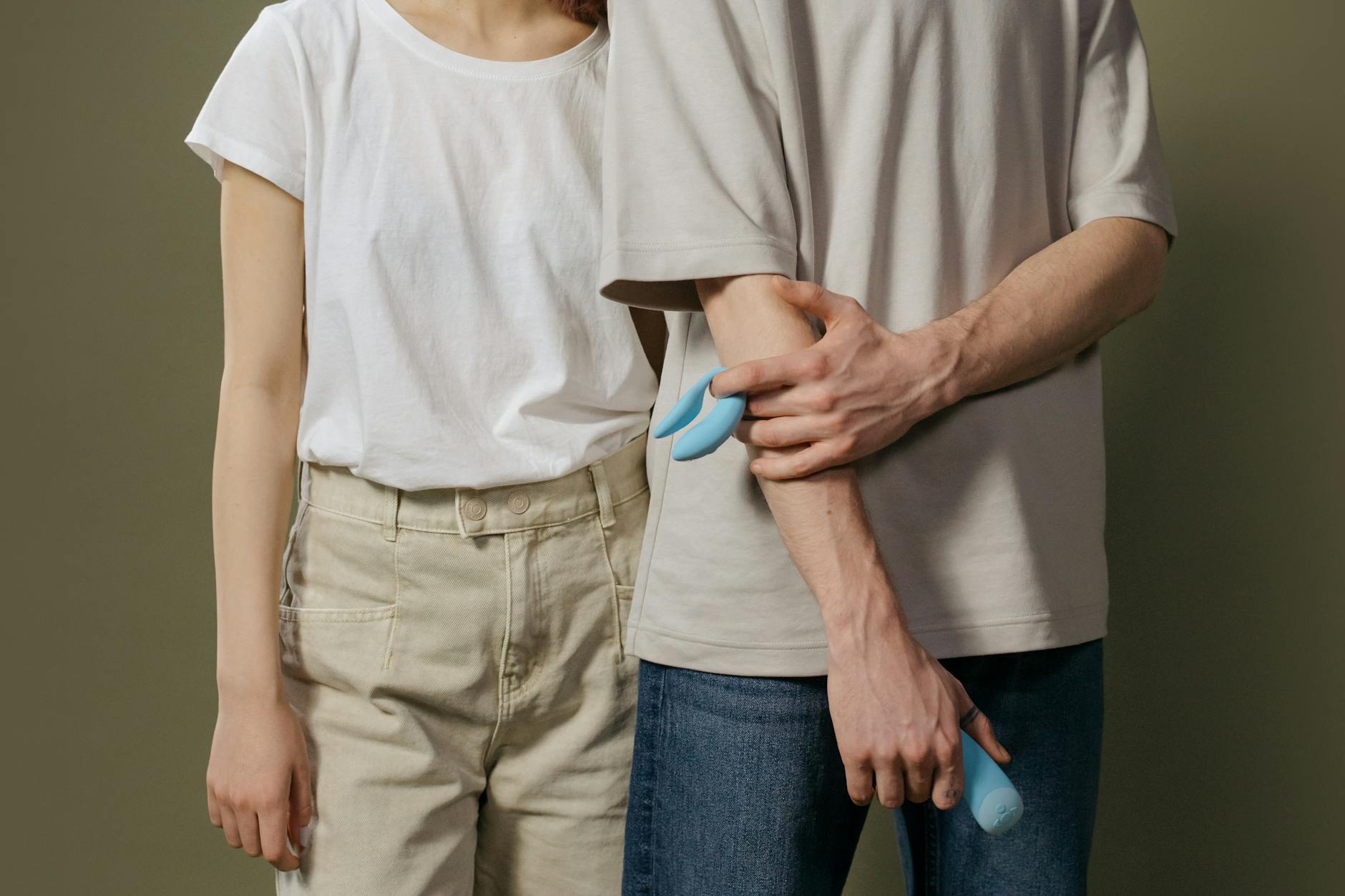 A young couple standing together indoors, exploring intimacy with modern tools and trust.