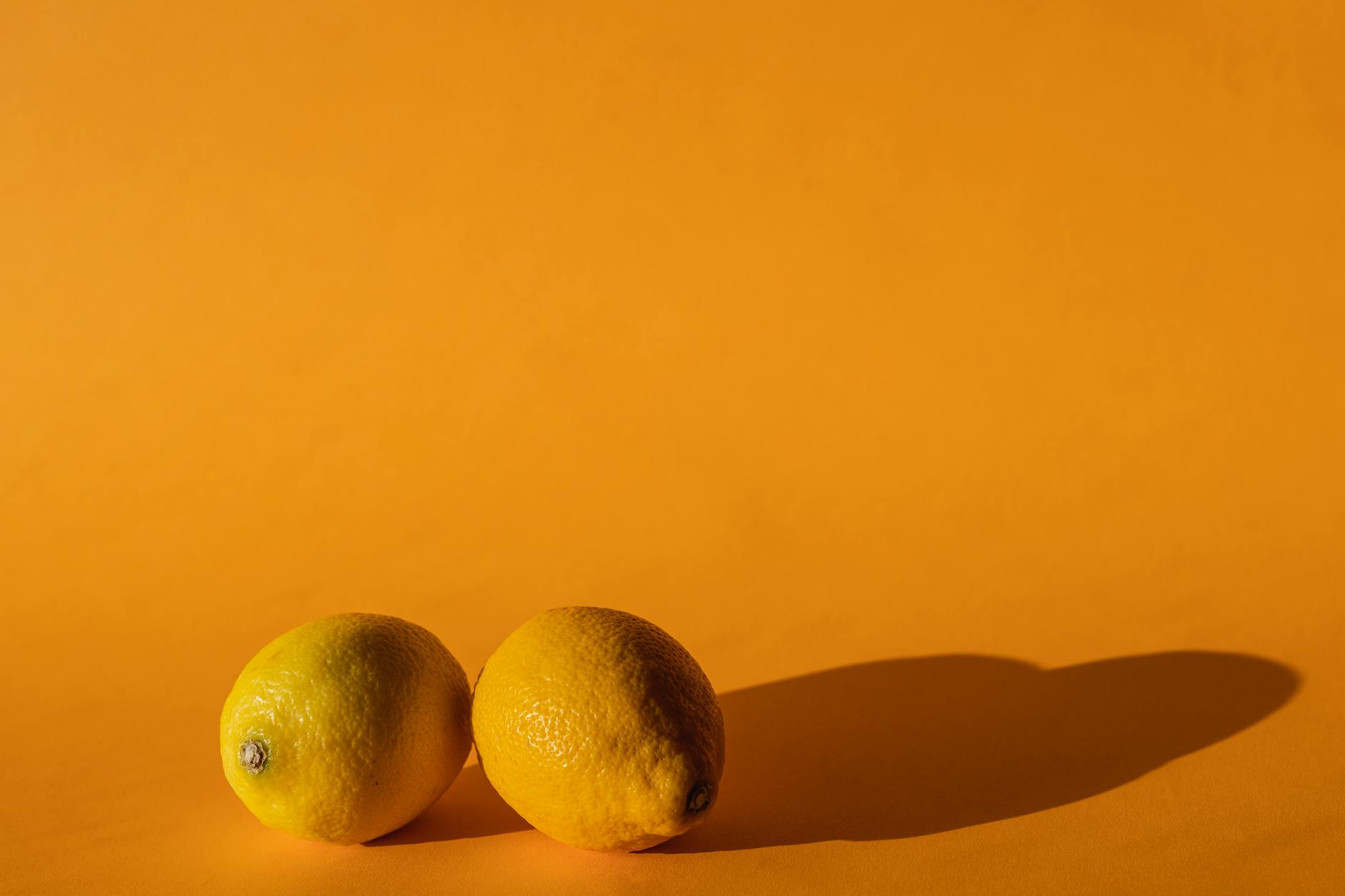 Hand holding a bright lemon against a vivid yellow background